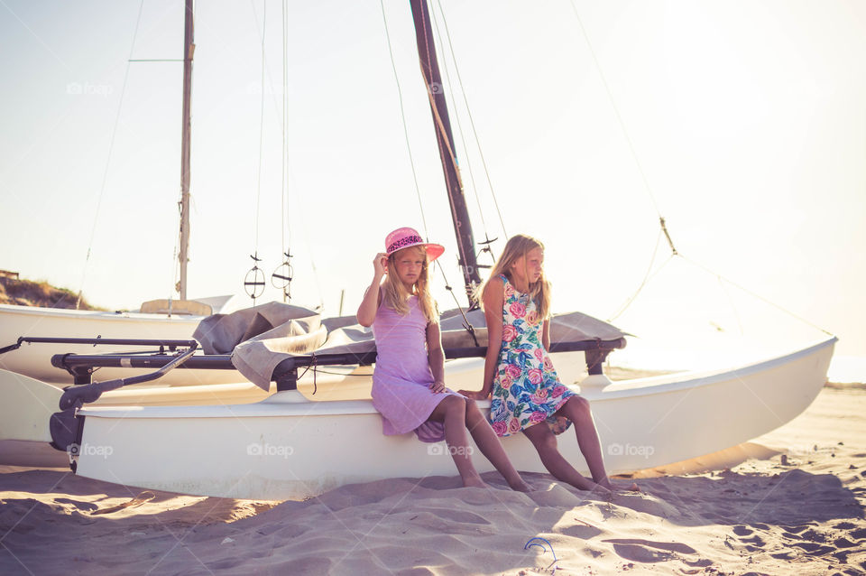 girls are sitting the boat on the beach enjoing sun