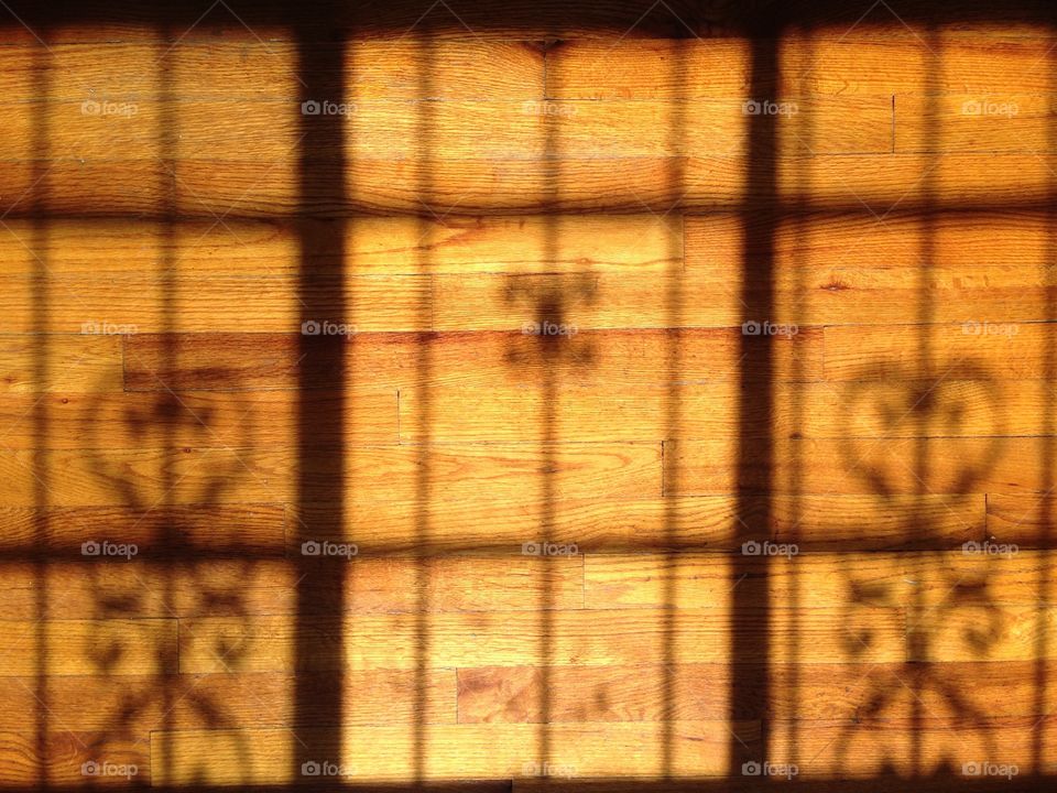 Shadow of a window grating on wooden floor 