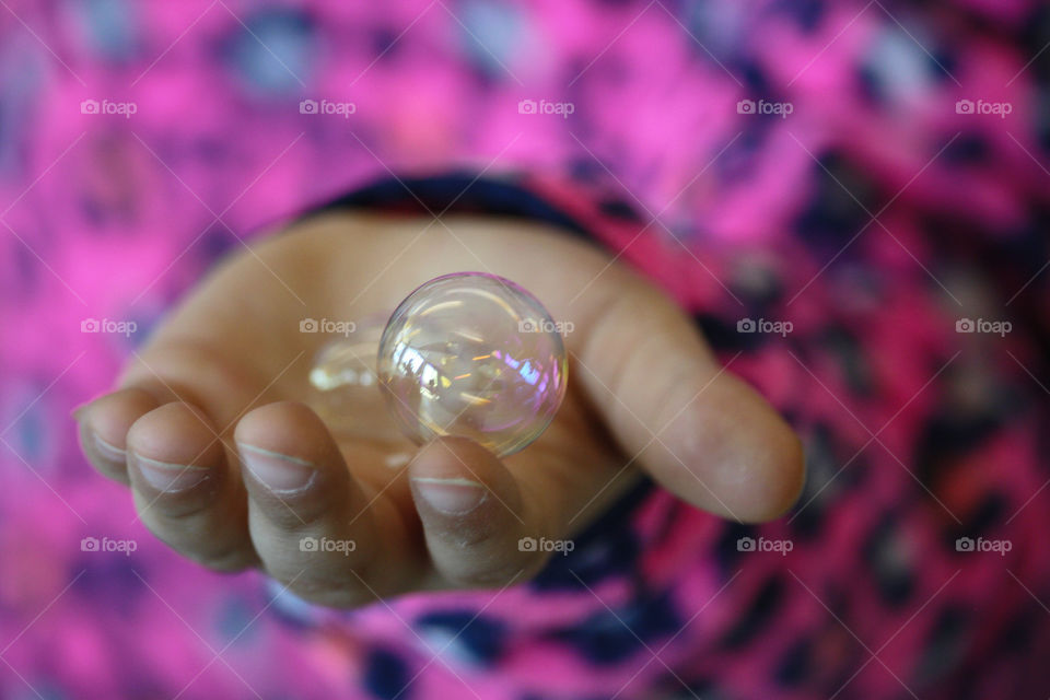 Child's hand holding soapy bubbles