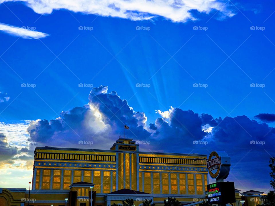 Storm clouds buuld behind the South Point hotel and casino in Las Vegas and sunlight shafts shoot out of the clouds