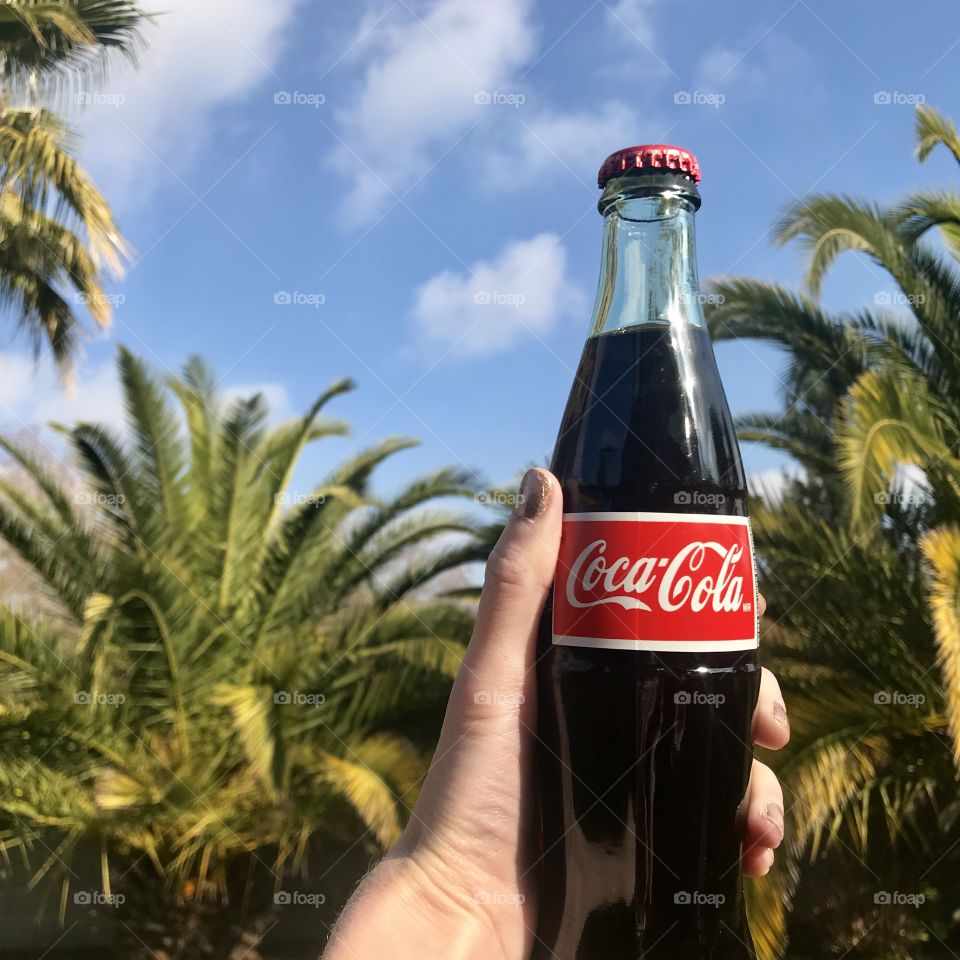 Holding a coke by the tropical palm trees 