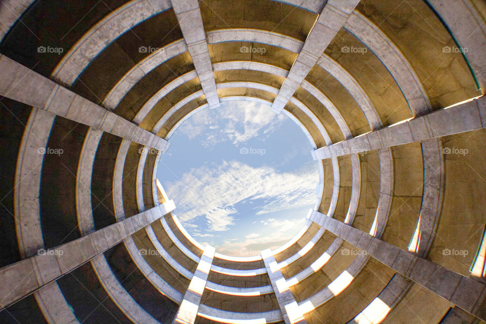 Looking upwards through parking deck towards sky. Very geometric spiral design.
