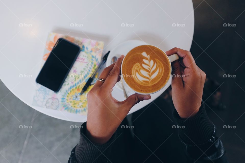 Woman raising a cup of cappuccino.