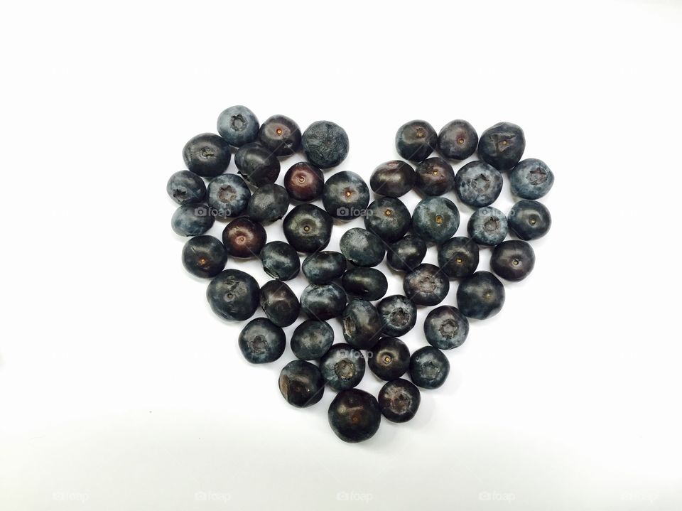 Heart made of blueberries on white background 