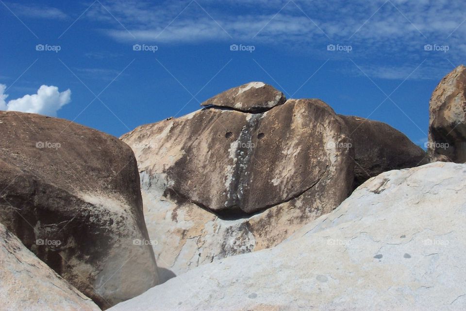 Smiling face on rock boulder against blue sky