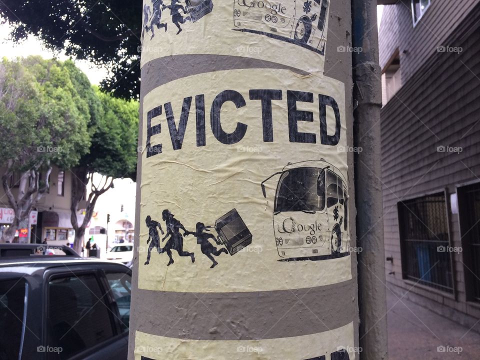 Evicted sign with a google bus chasing a family out of a neighborhood 