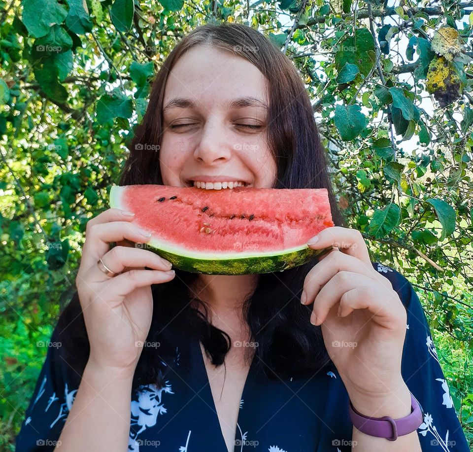 a girl enjoys a piece of fresh watermelon from her own garden