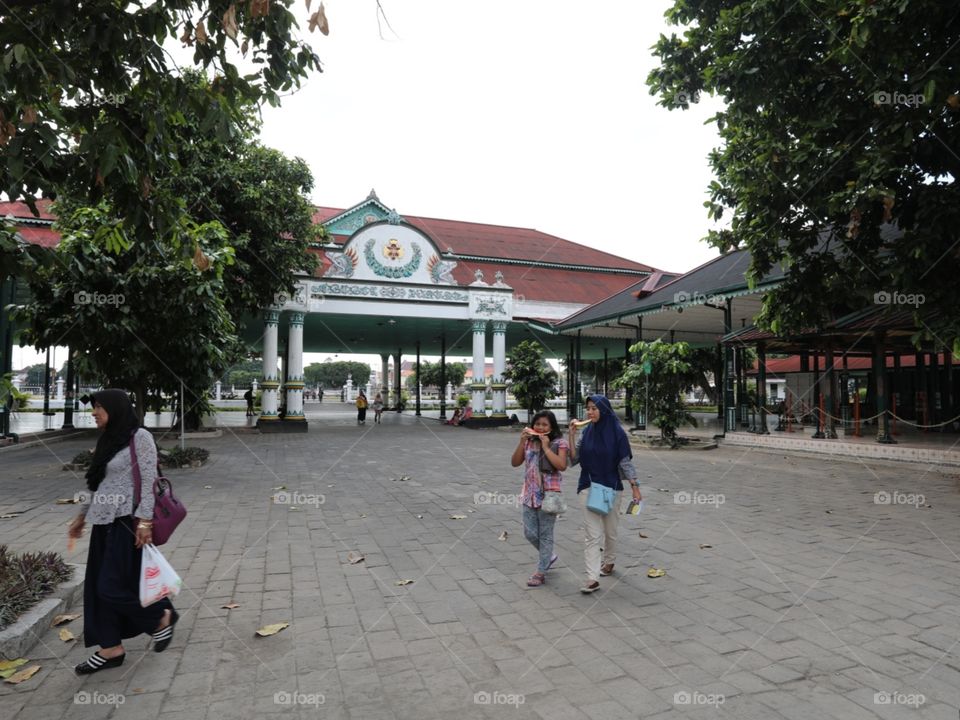 Two girls eat slices of watermelon while walking through the grounds of the Sultan's Palace in Yogyakarta, Indonesia