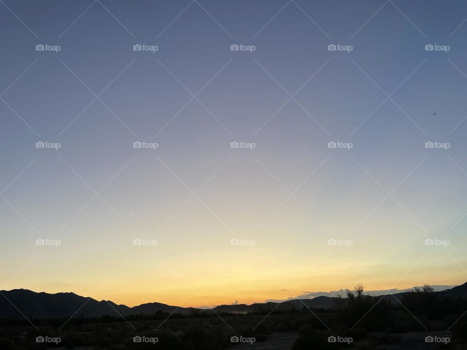 A yellow and blue sunset with mountains.