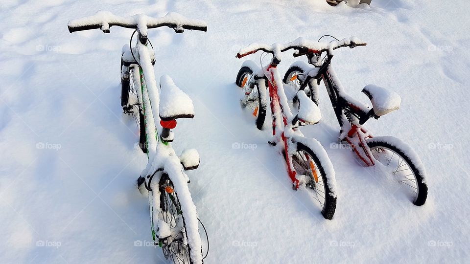 Snow-covered bicycles.