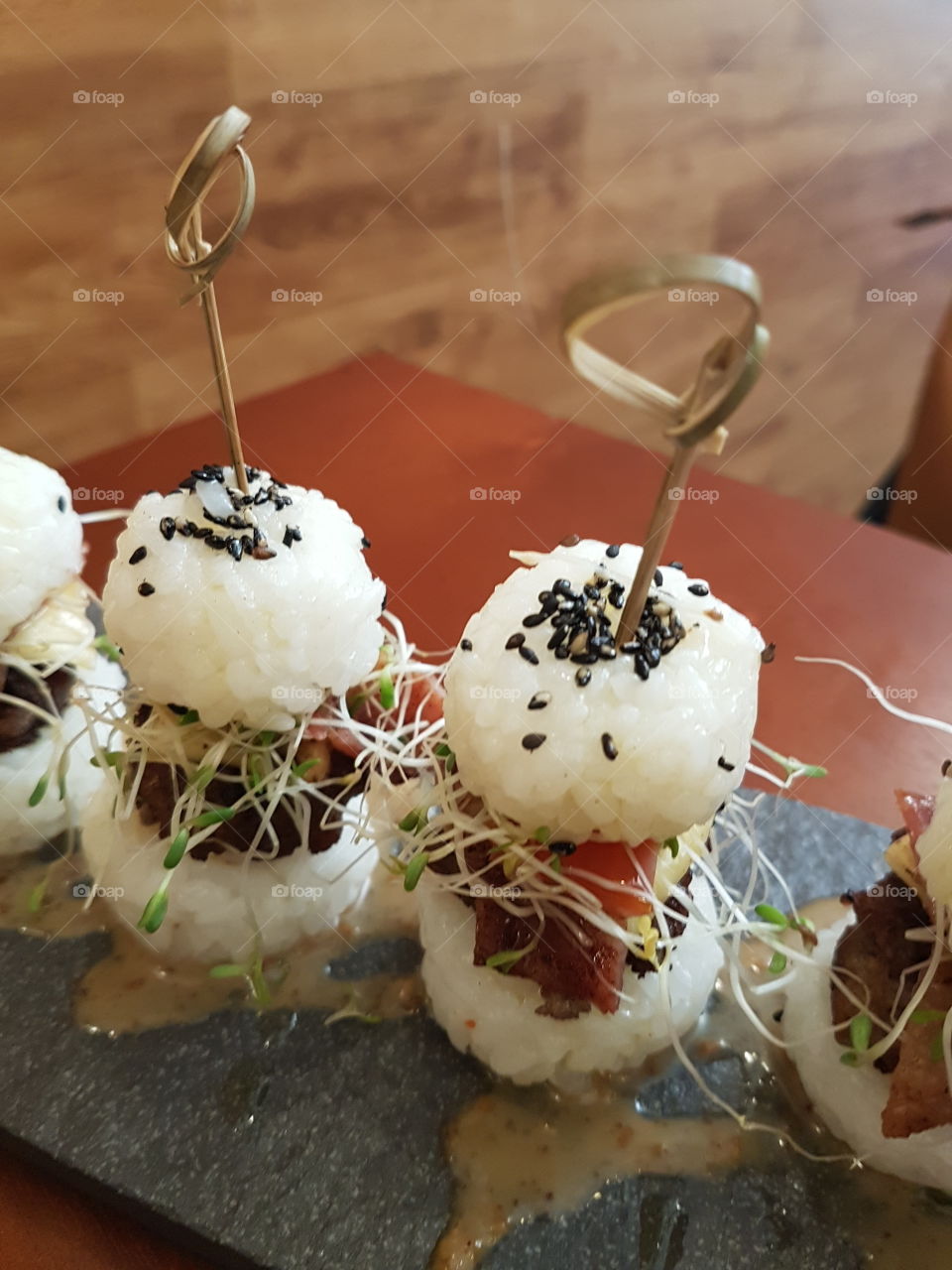 Sushi reinvented: truffled bacon cheeseburger sushi with alfalfa sprouts and truffle oil sesame sauce
