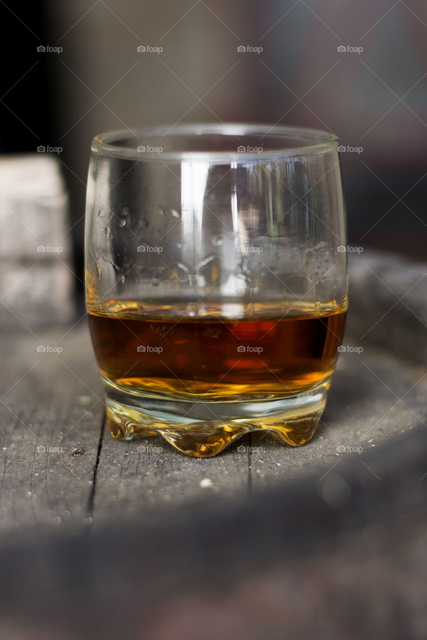 whiskey neat without ice. glass of neat whiskey without ice on barrel