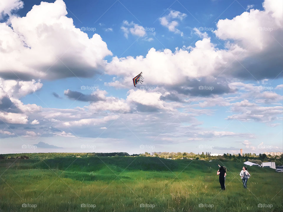 Happy family running a flying kite together in the green field in the countryside 