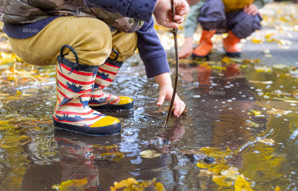 Little boys feet in puddle snow n rubber boots 