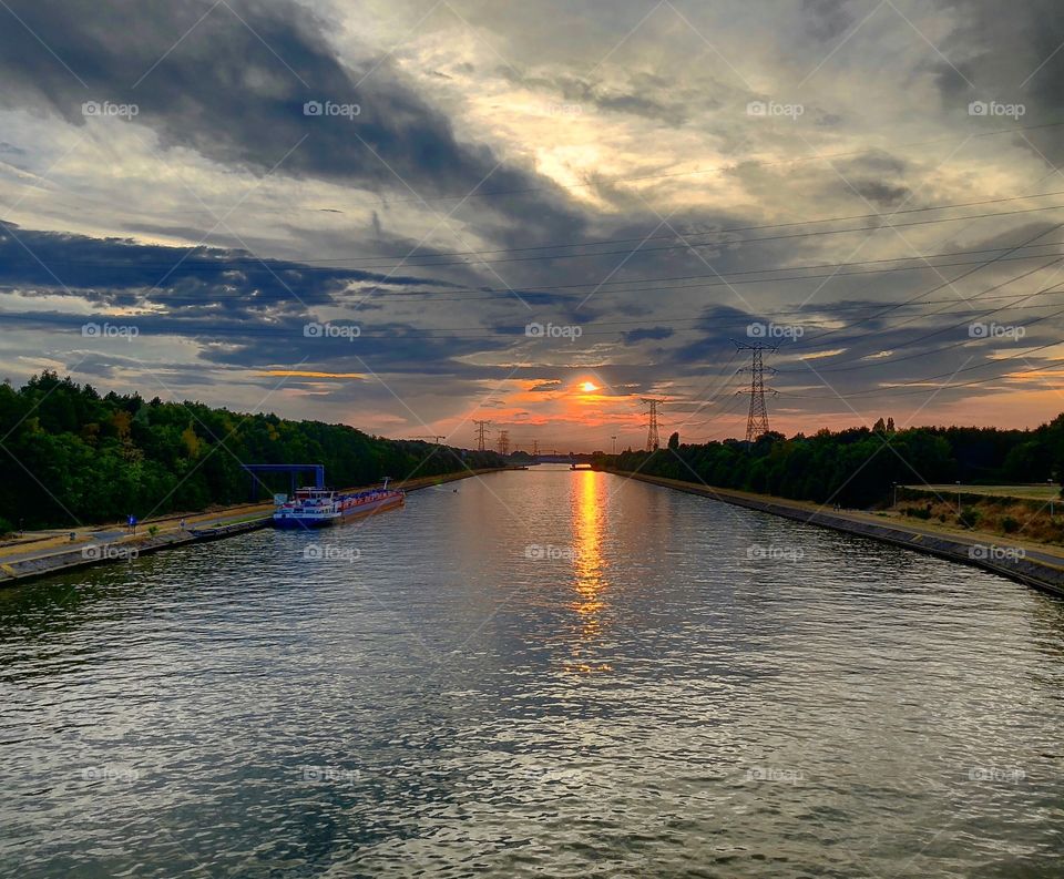 Cloudy sunset over a canal with a boat