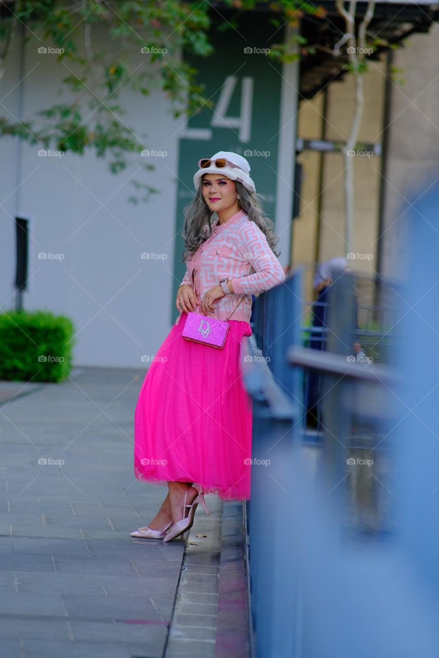 A woman wearing a pink skirt looks like a Barbie doll with blonde long hair. Fashionable concept photography.