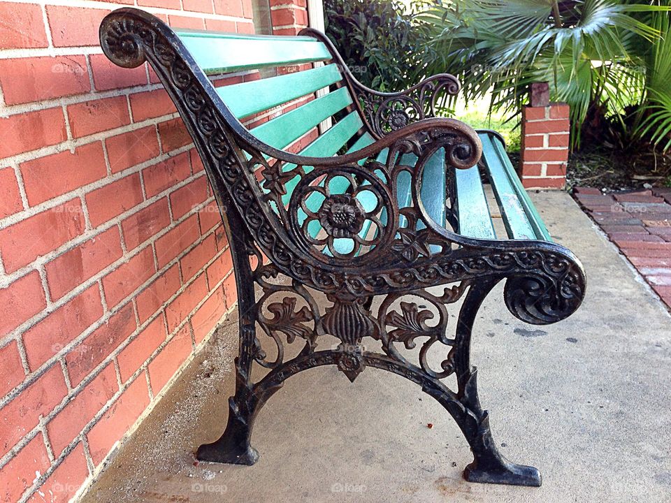 Antique green bench against a red brick wall-symmetry.