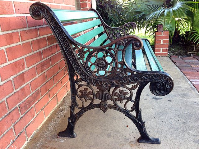 Antique green bench against a red brick wall-symmetry.