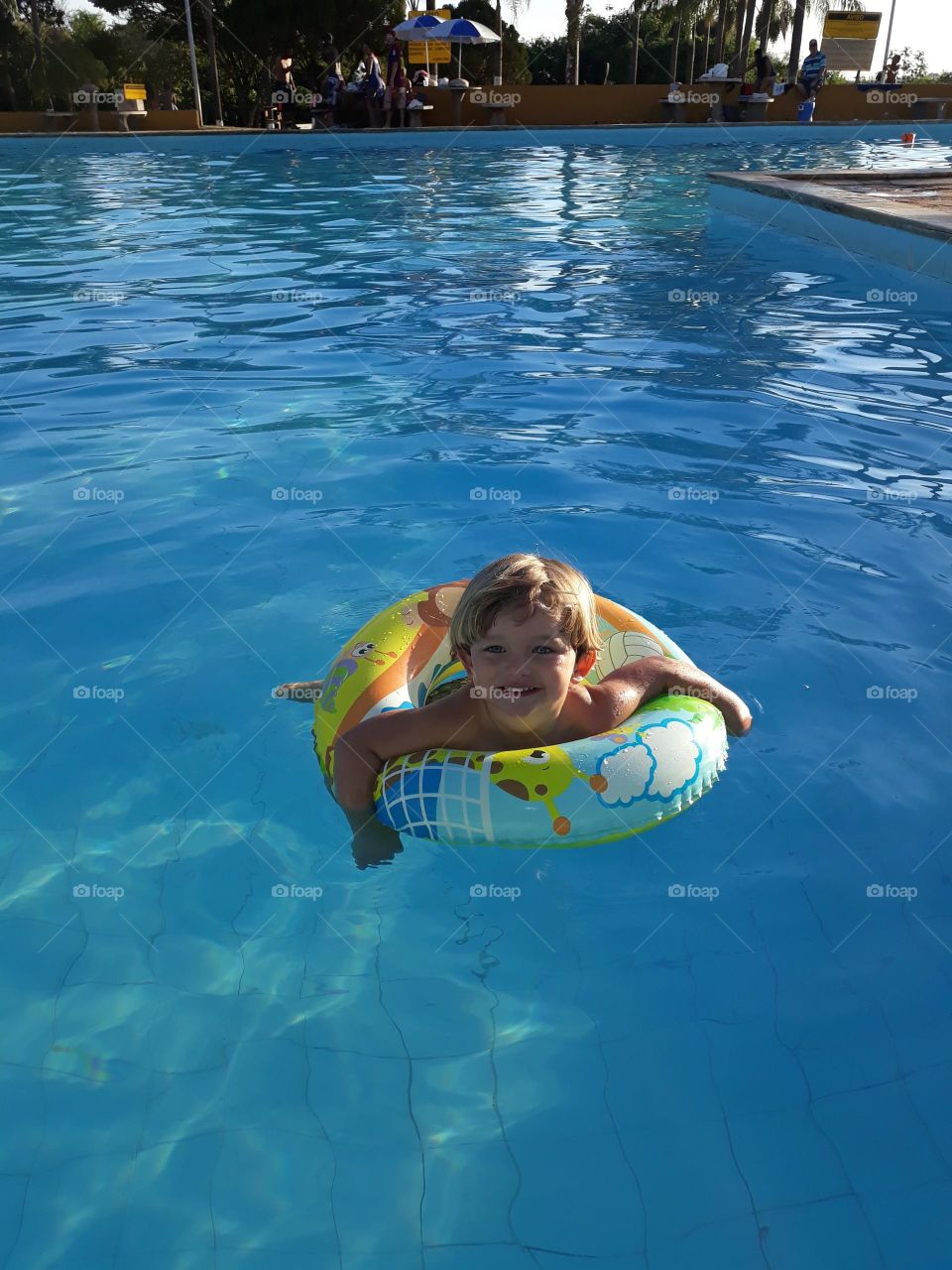 child playing with the float in the blue pool