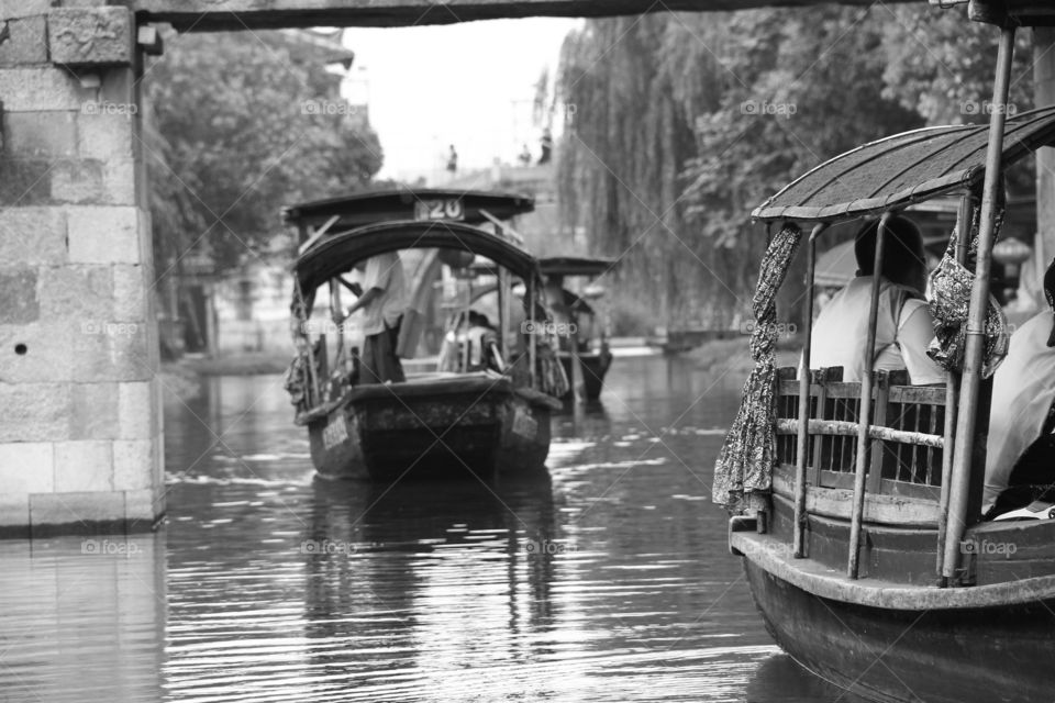 A black and white portrait of some typical traditional chinese boats on a river in China. it is a typical tourist attraction.