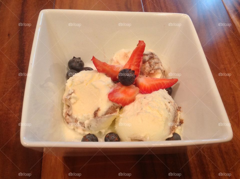 A photo of Vanilla ice cream with strawberries and blueberries. 