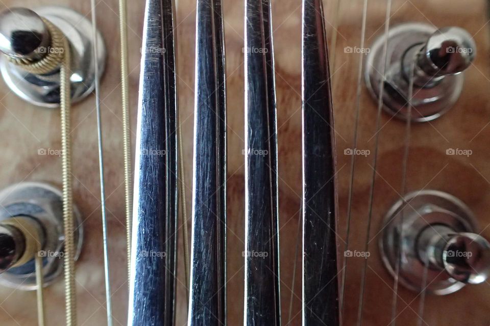 Tuning fork over 12 string guitar tuning peg board closeup