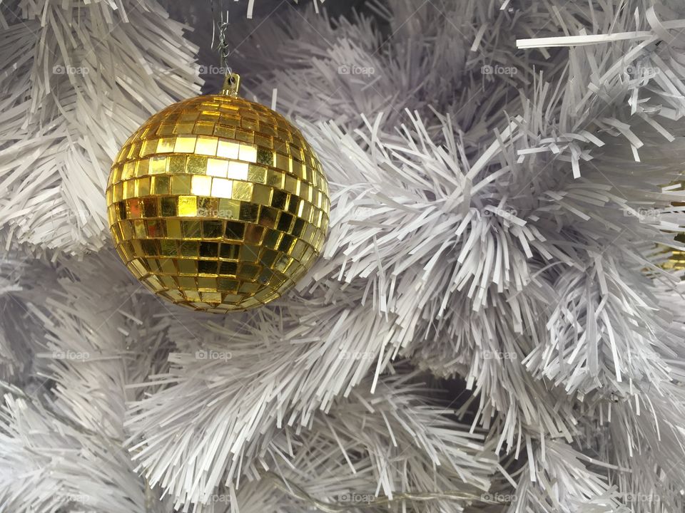 Golden ornament on white Christmas pine tree 