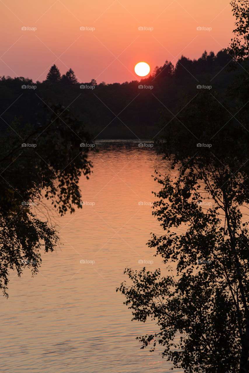Colorful sunset in the forest, sunlight reflection in the lake 