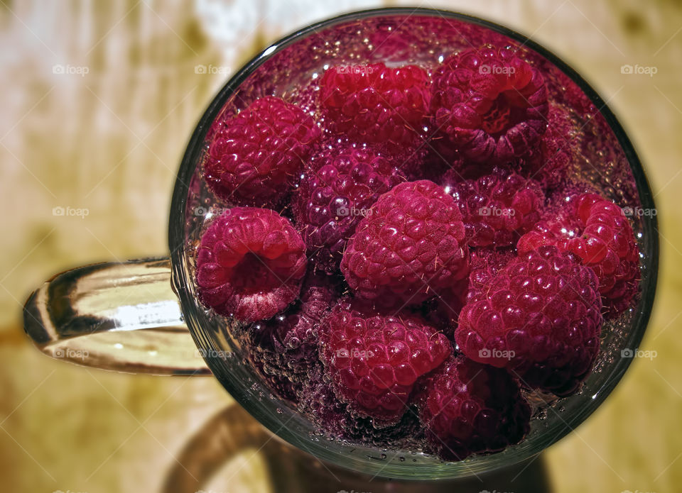 Cup of raspberries in bubbly water