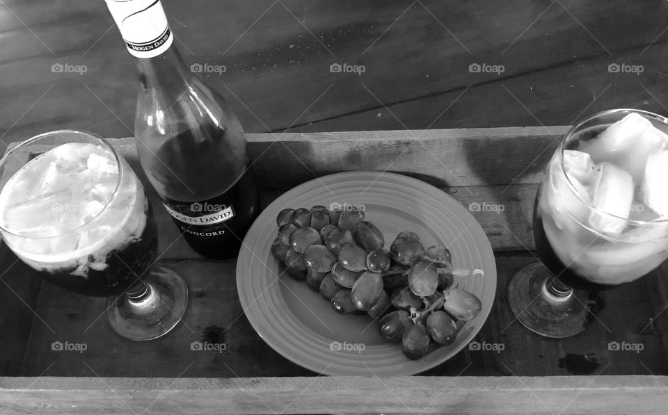 Wine, grapes and two wine glasses sitting in a vintage wooden type tray. 