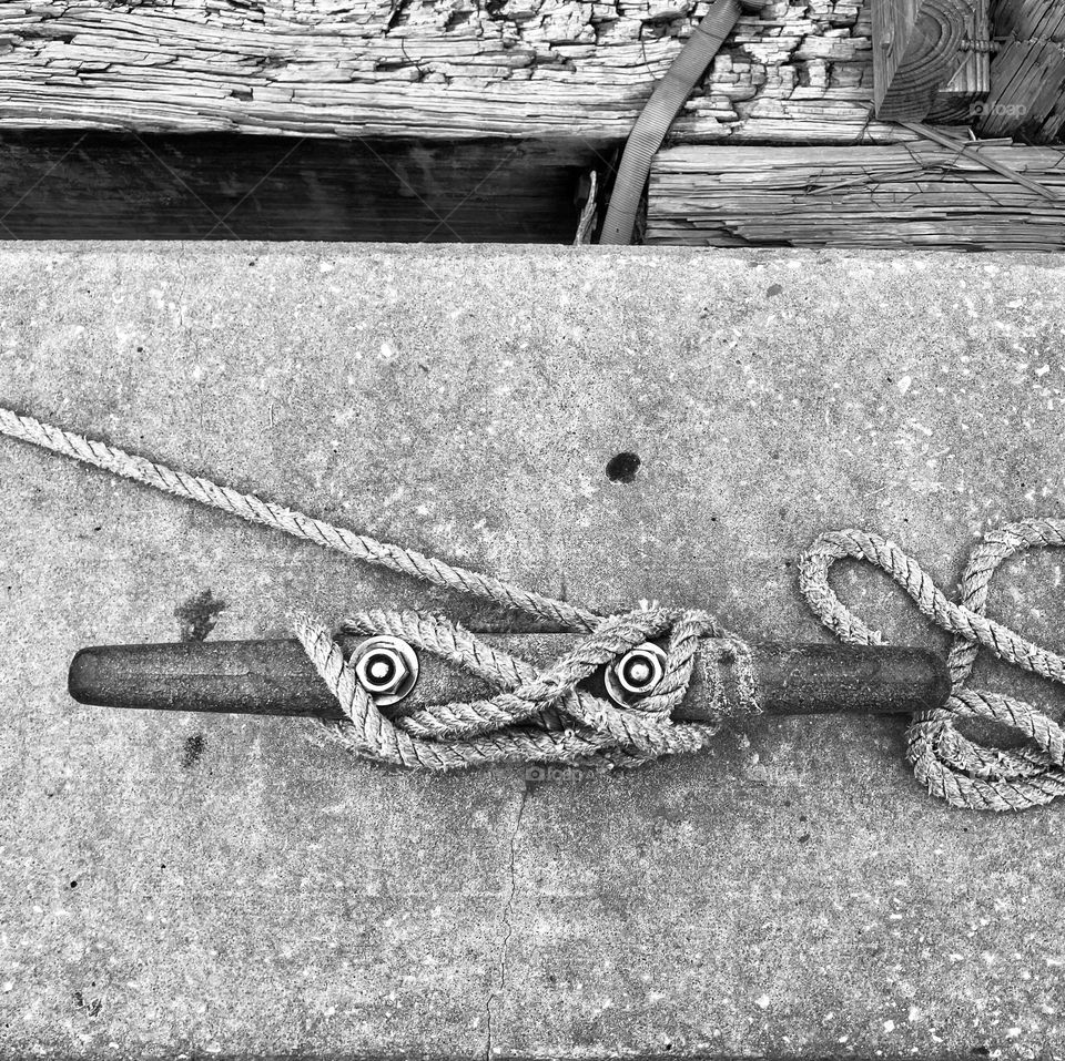 Black and white image of rope hitched to cleat in dock in Tarpon Springs, Florida