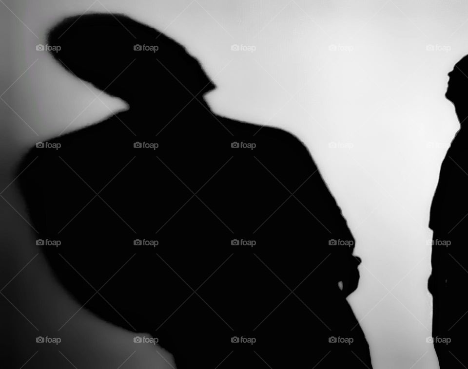 Silhouette of a man looking at his shadow on a white wall