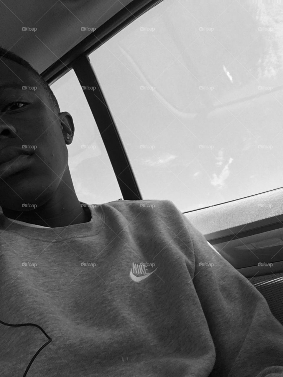 Black and white photo wearing a grey Nike sweater with a serious halve face on the pic in a car 