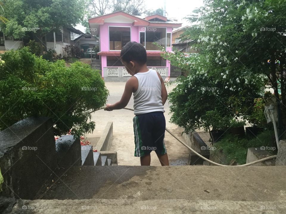 A little boy watering the plants