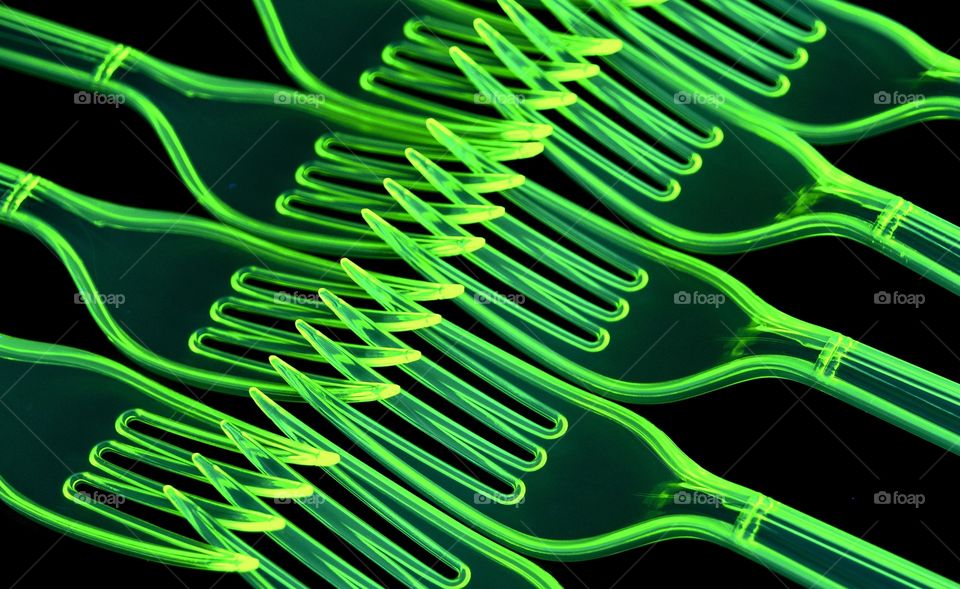 Abstract green plastic forks under black light 