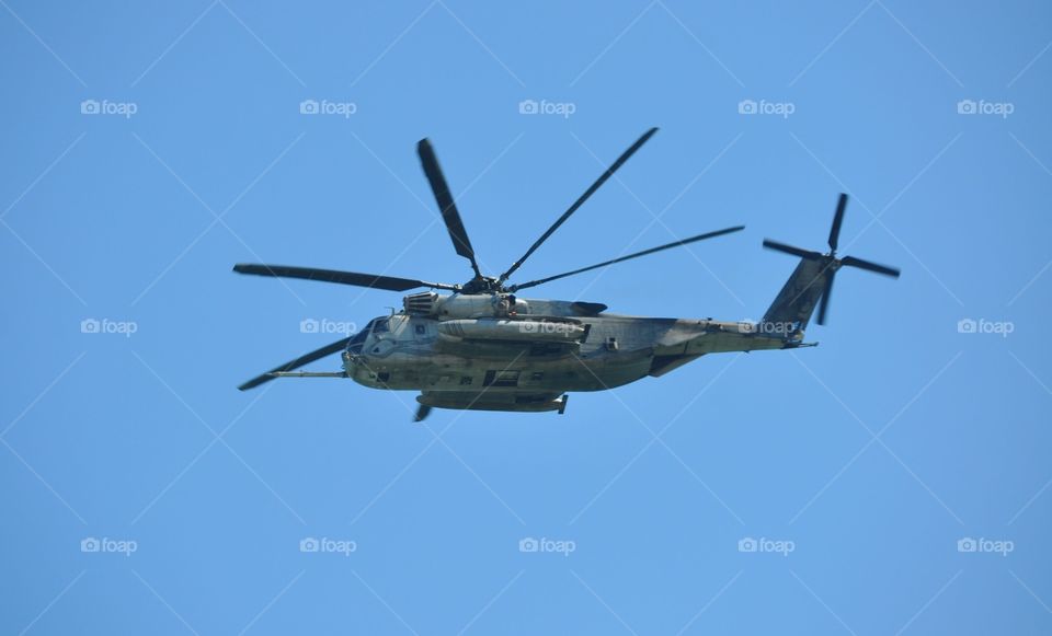 A US military Blackhawk helicopter in-flight against the blue sky.