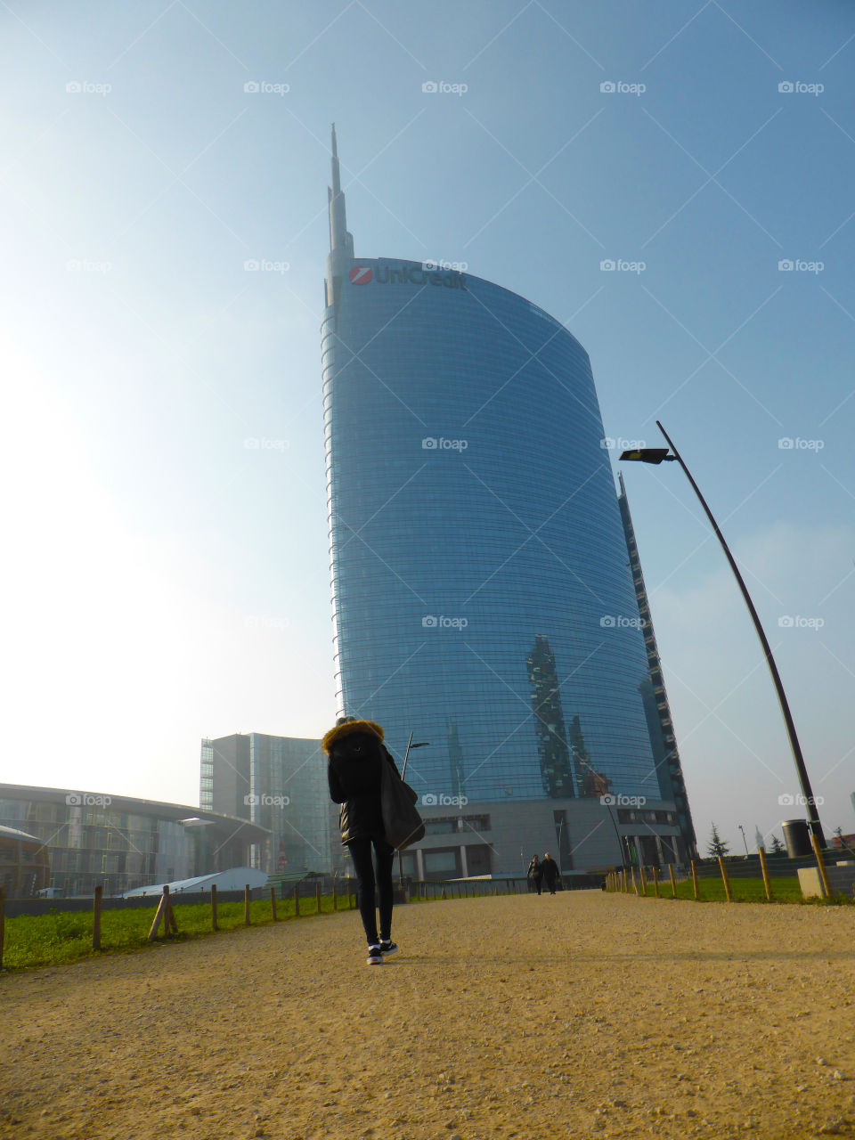 A person is Walking in the park near the Unicredit skyscraper in Milan
