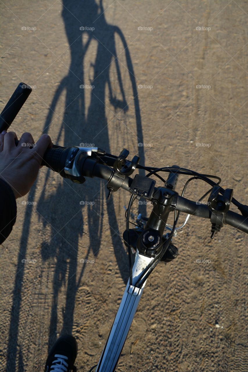 person riding on a bike and shadows on a rural road