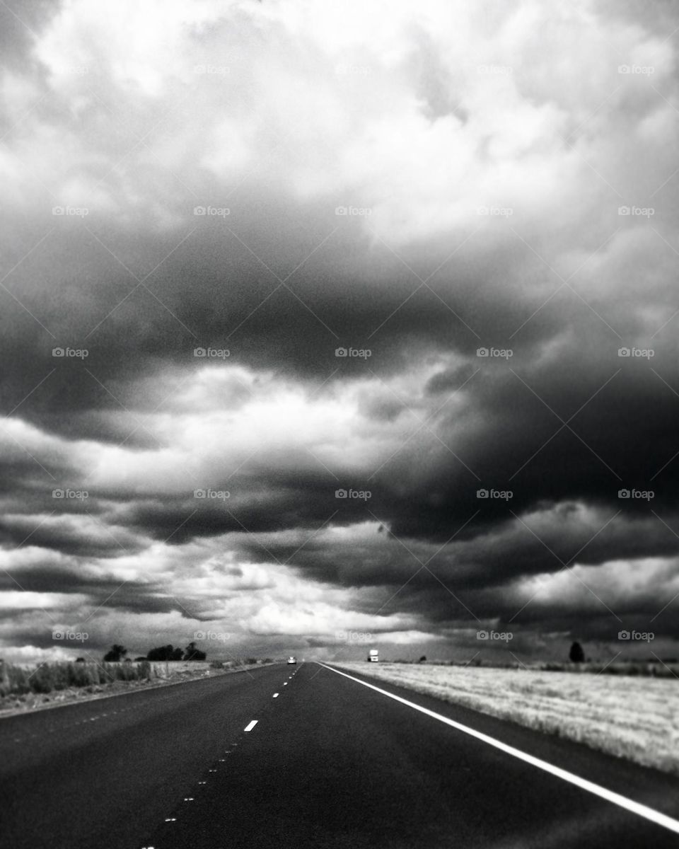 A long road: highway drive on a cloudy day. Clouds. Rain clouds. Road. Highway. Fields. 