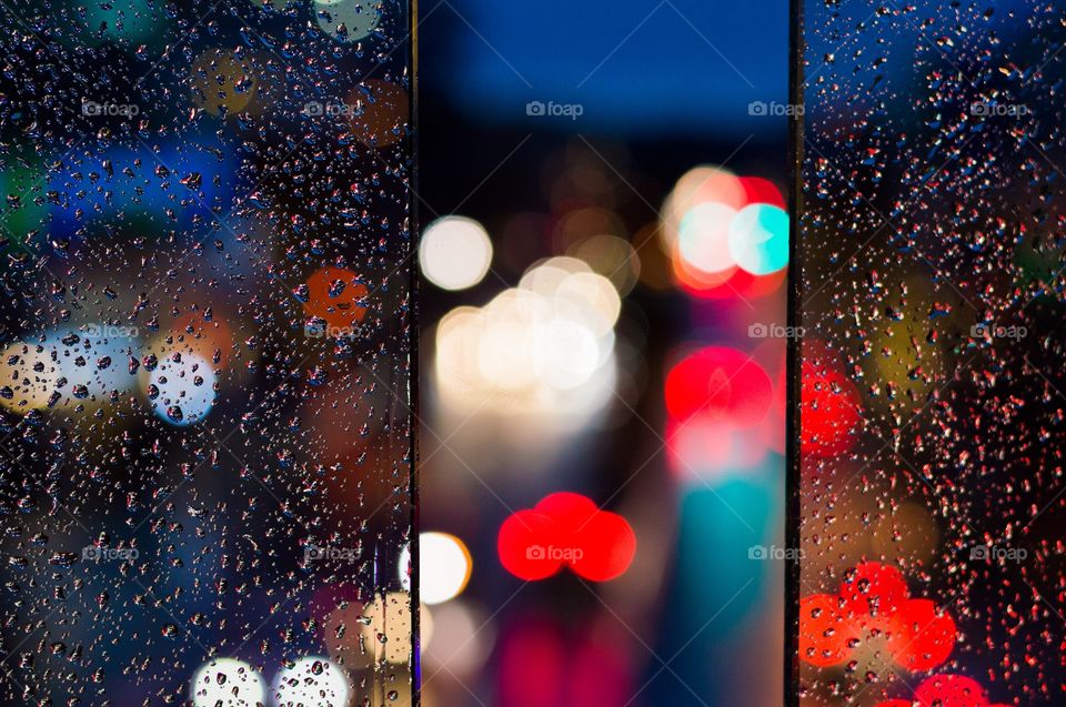 Rainy day bokeh. Rain on the glass sides of a sky bridge with bokeh of car lights in traffic.