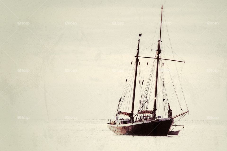 A lone yacht floating on a calm ocean with a vintage texture.