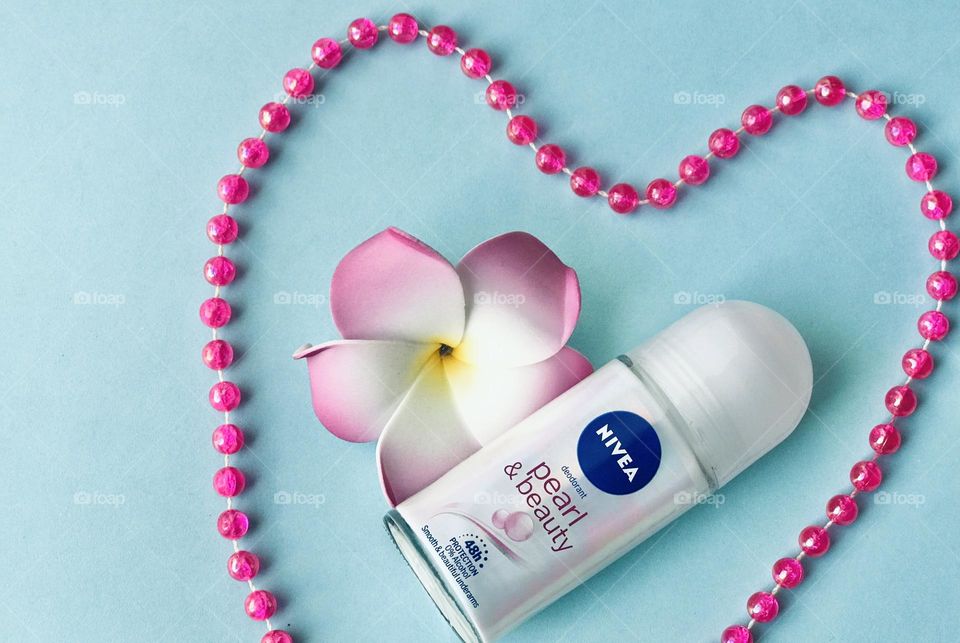 Nivea pearl and beauty roll on deodorant between pink pearl chain and frangipanni flower.