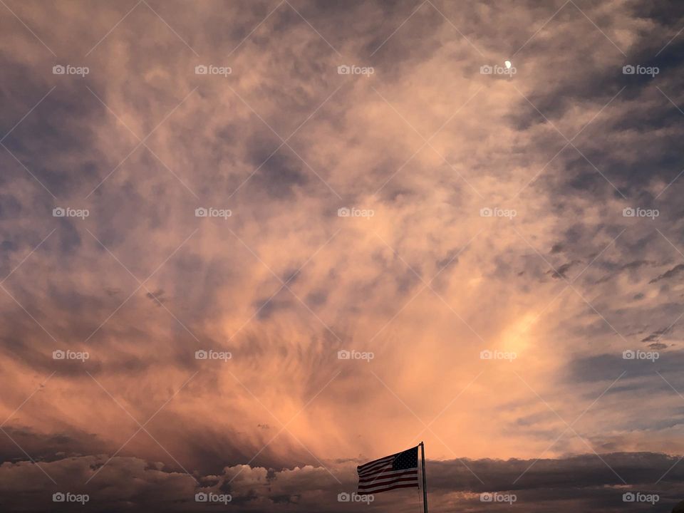 Cloudy sunset with American flag and moon