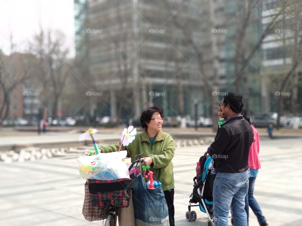 Hello You ! 
Some pictures says many things. A Hocker trying to sell something. Happy Moment. Spring already come. Flowers are blossoming. Photographers are ready for Capture. This awesome picture captured from my campusTianjin University, China.