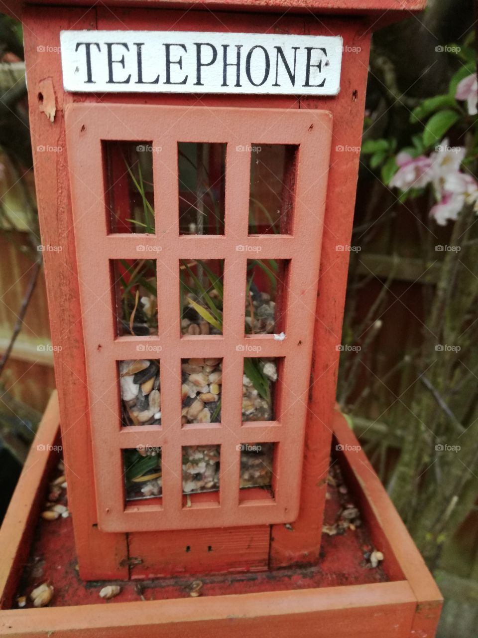 A mini phone box bird feeder with seeds in it.