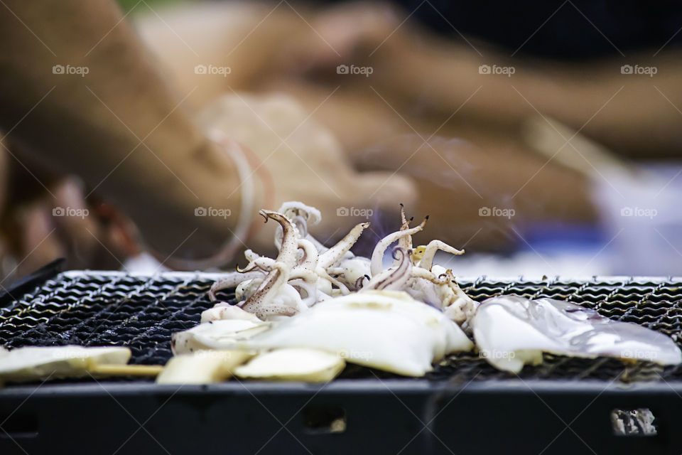 Fresh squid and mushrooms on the grill grate steel.