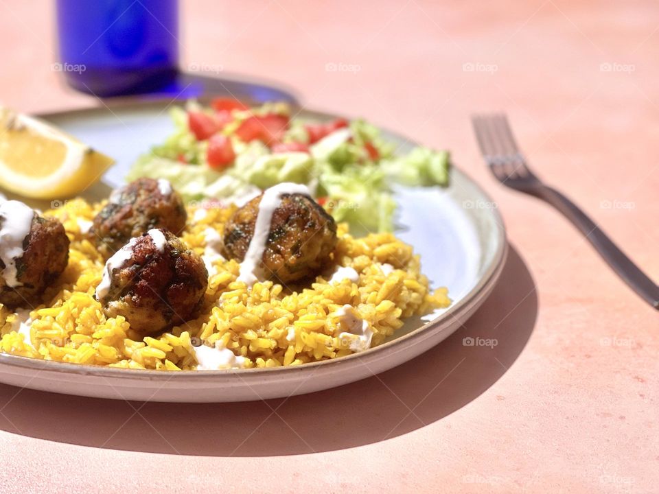 Hard light closeup of a plate of chicken shawarma meatballs with basmati rice 