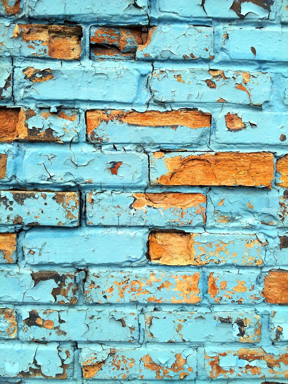 Brick wall with faded chipped blue paint