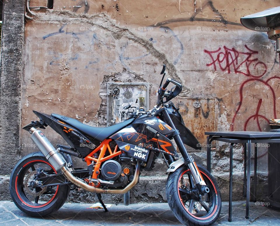 Supermoto. Racy motorcycle alongside an ancient graffiti covered wall  in Rome