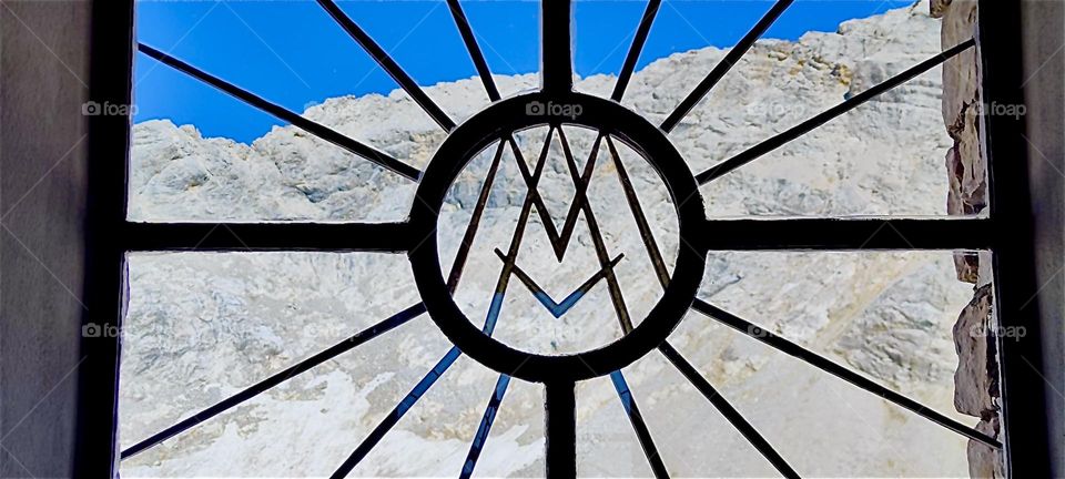 This beautiful symbolic cast iron grid covers a window of the “Mariä Heimsuchung” “Visitation of Mary” “Zugspitze” chapel on Germany’s highest peak of the “Wetterstein Mountains” in the “Alps”. 2024. Hypnotic Productions